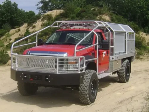Exterior view of small fire truck showing cab, body compartments, and wheel/tire area.