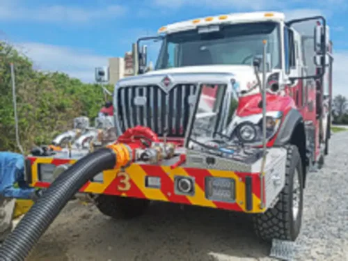 Exterior view of small fire truck showing cab, body compartments, and wheel/tire area.