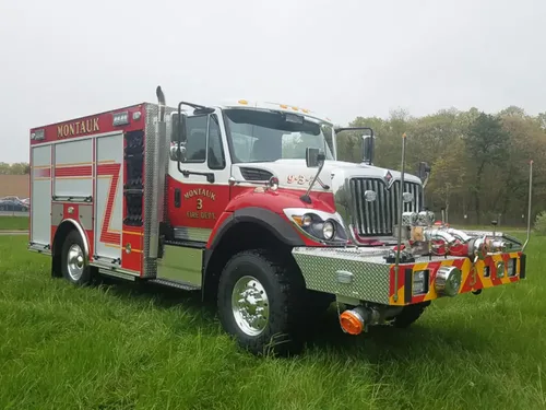 Exterior view of small fire truck showing cab, body compartments, and wheel/tire area.