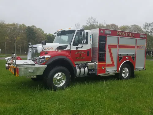 Exterior view of small fire truck showing cab, body compartments, and wheel/tire area.