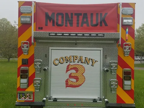 Exterior view of small fire truck showing cab, body compartments, and wheel/tire area.