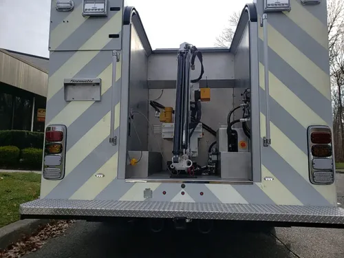 Exterior view of small fire truck showing cab, body compartments, and wheel/tire area.