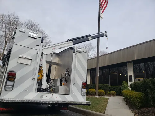 Exterior view of small fire truck showing cab, body compartments, and wheel/tire area.
