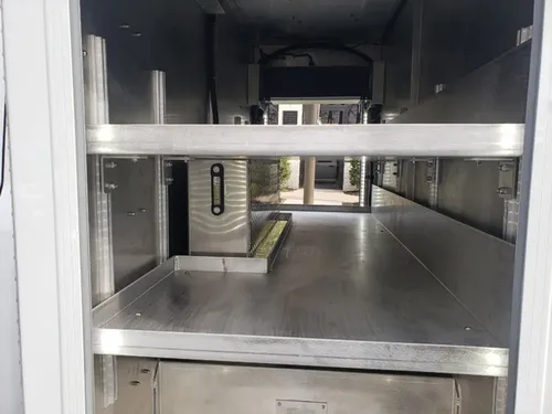 Exterior view of small fire truck showing cab, body compartments, and wheel/tire area.