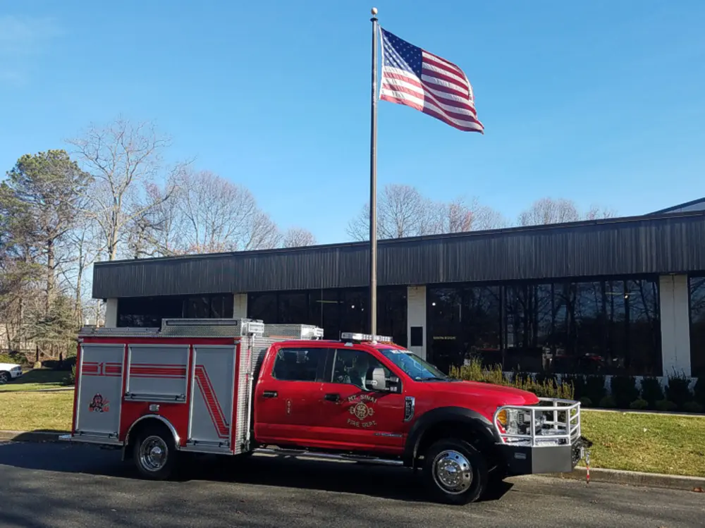 Exterior view of small fire truck showing cab, body compartments, and wheel/tire area.