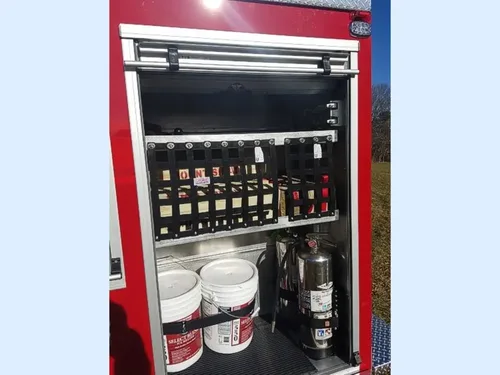 Exterior view of small fire truck showing cab, body compartments, and wheel/tire area.