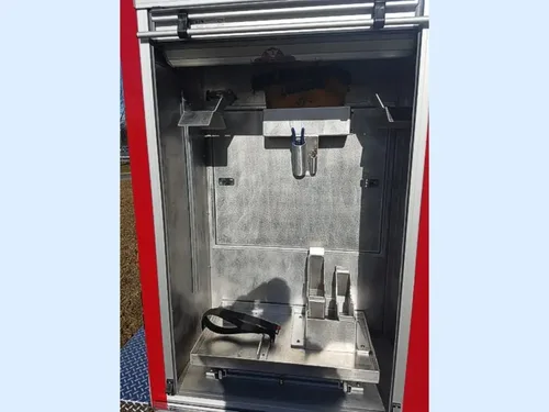 Exterior view of small fire truck showing cab, body compartments, and wheel/tire area.