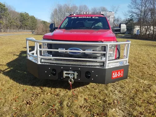 Exterior view of small fire truck showing cab, body compartments, and wheel/tire area.