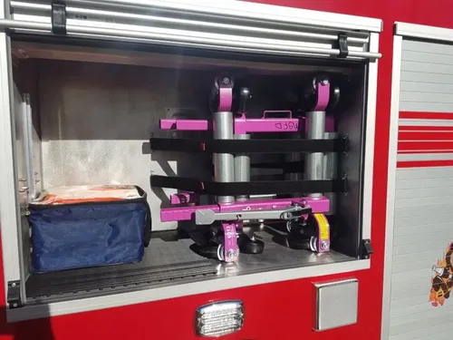 Exterior view of small fire truck showing cab, body compartments, and wheel/tire area.