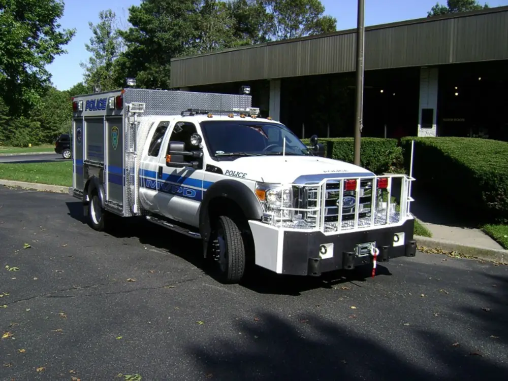 Exterior view of small fire truck showing cab, body compartments, and wheel/tire area.