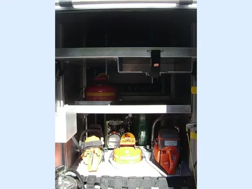 Exterior view of small fire truck showing cab, body compartments, and wheel/tire area.