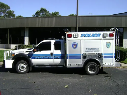 Exterior view of small fire truck showing cab, body compartments, and wheel/tire area.