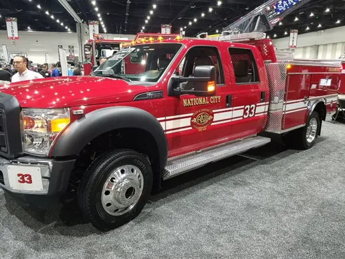 Exterior view of small fire truck showing cab, body compartments, and wheel/tire area.