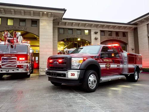 Exterior view of small fire truck showing cab, body compartments, and wheel/tire area.