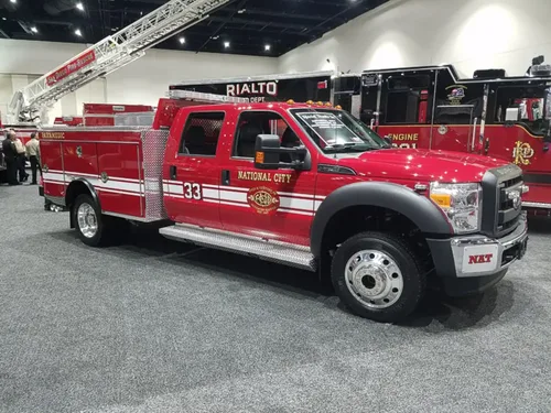 Exterior view of small fire truck showing cab, body compartments, and wheel/tire area.