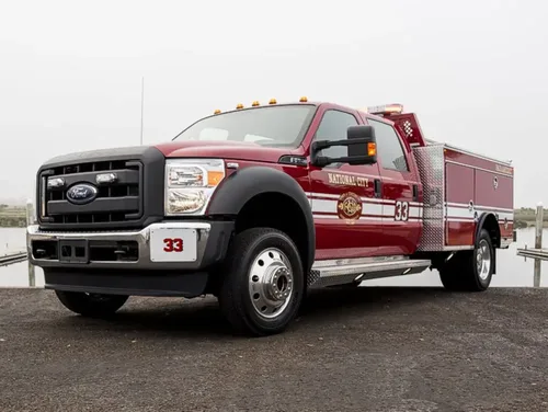 Exterior view of small fire truck showing cab, body compartments, and wheel/tire area.