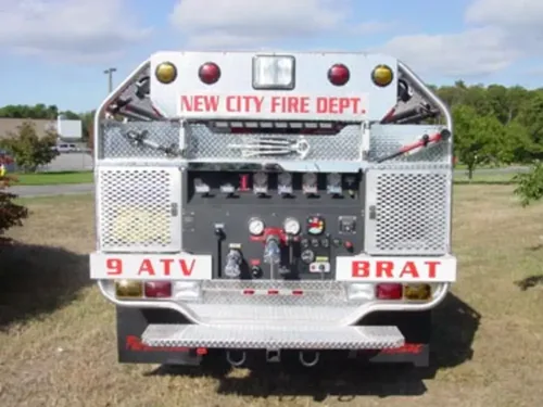 Exterior view of small fire truck showing cab, body compartments, and wheel/tire area.