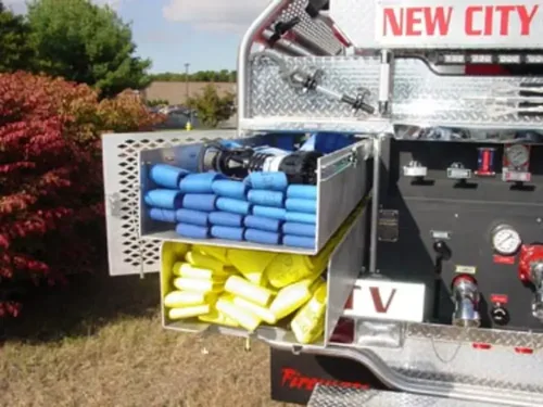 Exterior view of small fire truck showing cab, body compartments, and wheel/tire area.