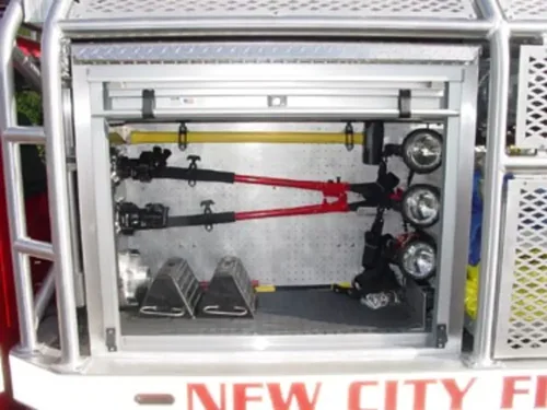 Exterior view of small fire truck showing cab, body compartments, and wheel/tire area.