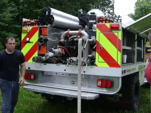 Exterior view of small fire truck showing cab, body compartments, and wheel/tire area.
