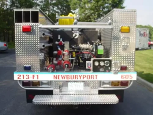 Exterior view of small fire truck showing cab, body compartments, and wheel/tire area.