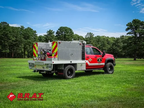 Exterior view of small fire truck showing cab, body compartments, and wheel/tire area.