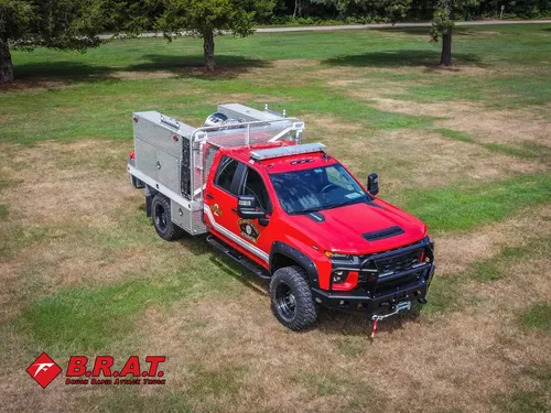 Exterior view of small fire truck showing cab, body compartments, and wheel/tire area.