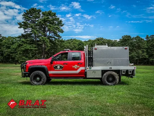 Exterior view of small fire truck showing cab, body compartments, and wheel/tire area.