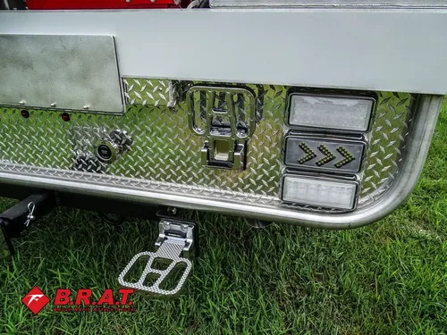 Exterior view of small fire truck showing cab, body compartments, and wheel/tire area.