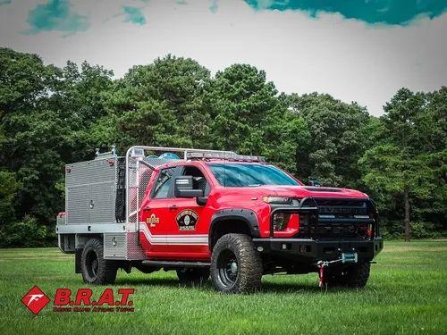 Exterior view of small fire truck showing cab, body compartments, and wheel/tire area.