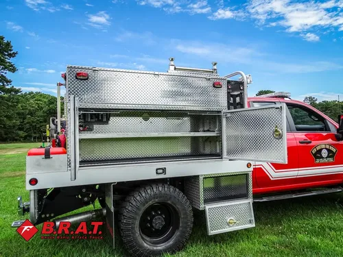 Exterior view of small fire truck showing cab, body compartments, and wheel/tire area.