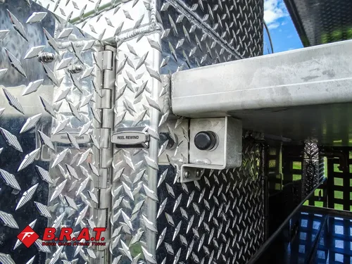 Exterior view of small fire truck showing cab, body compartments, and wheel/tire area.