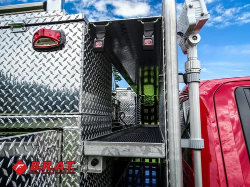 Exterior view of small fire truck showing cab, body compartments, and wheel/tire area.