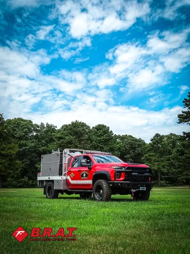 Exterior view of small fire truck showing cab, body compartments, and wheel/tire area.