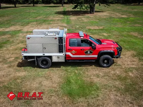 Exterior view of small fire truck showing cab, body compartments, and wheel/tire area.