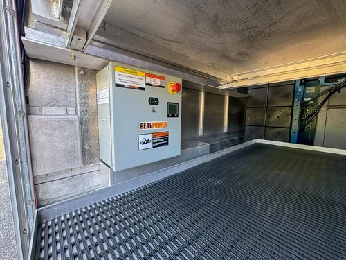 Large compartment interior with empty floor and utility panels on wall.