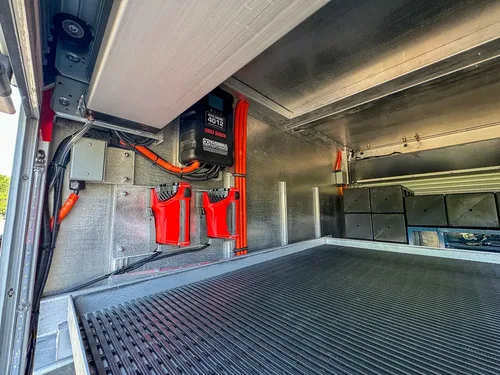 Compartment interior with mounted charger and orange wiring on side wall.