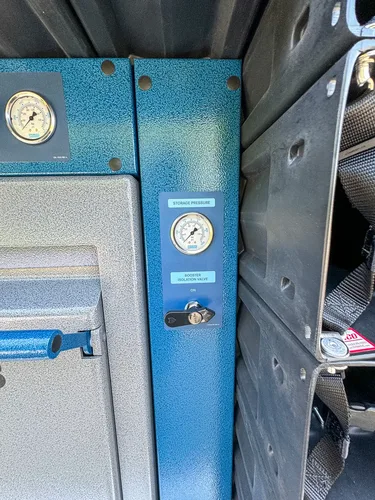 Blue control plate close-up with pressure gauge and valve handle.