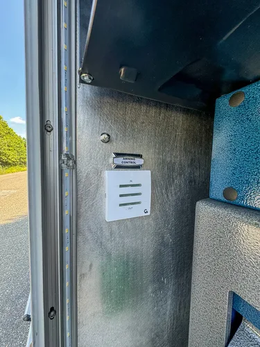 Narrow compartment panel with warning labels and vented slots.