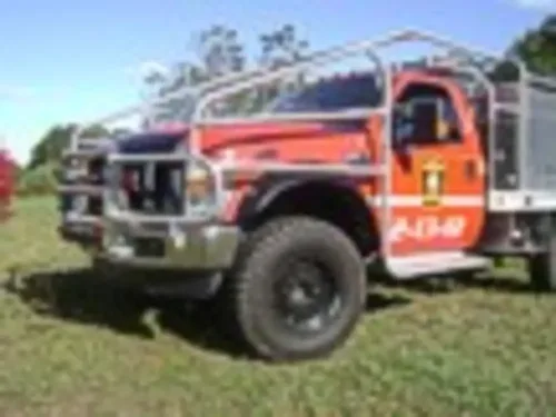 Exterior view of small fire truck showing cab, body compartments, and wheel/tire area.