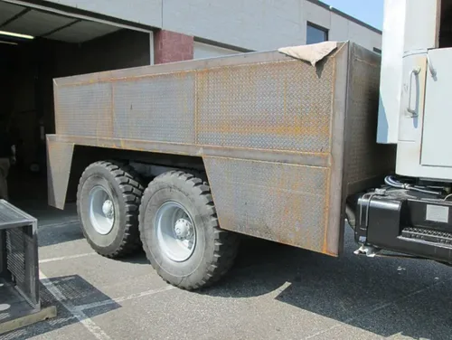 Exterior view of small fire truck showing cab, body compartments, and wheel/tire area.