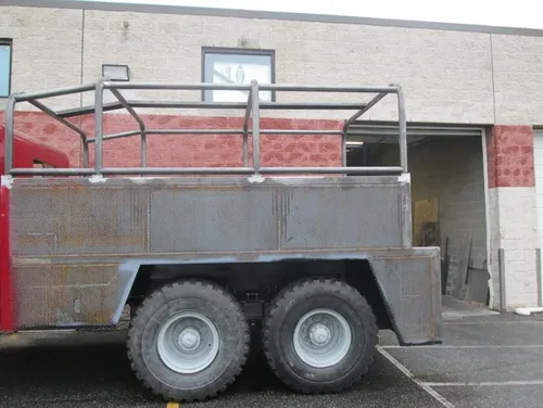 Exterior view of small fire truck showing cab, body compartments, and wheel/tire area.