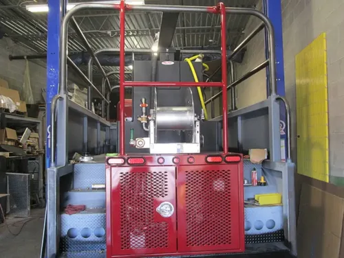 Exterior view of small fire truck showing cab, body compartments, and wheel/tire area.