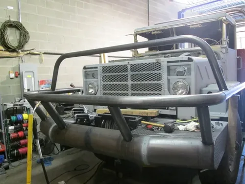 Exterior view of small fire truck showing cab, body compartments, and wheel/tire area.