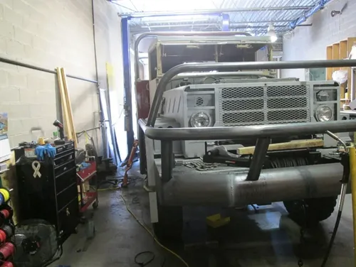 Exterior view of small fire truck showing cab, body compartments, and wheel/tire area.