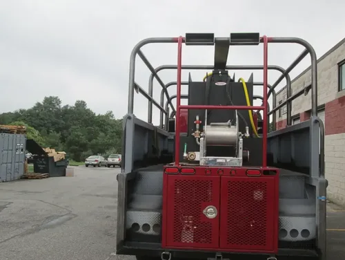 Exterior view of small fire truck showing cab, body compartments, and wheel/tire area.