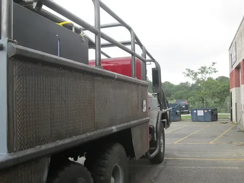 Exterior view of small fire truck showing cab, body compartments, and wheel/tire area.