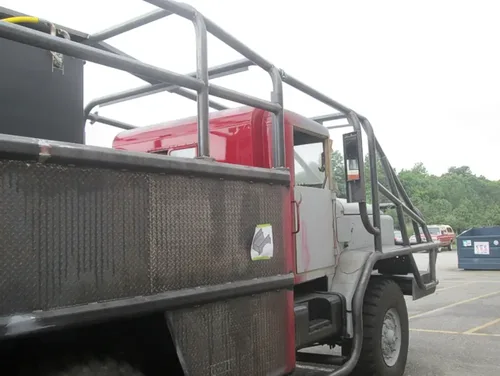 Exterior view of small fire truck showing cab, body compartments, and wheel/tire area.