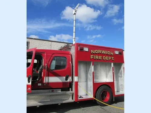 Exterior view of small fire truck showing cab, body compartments, and wheel/tire area.