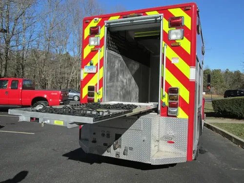Exterior view of small fire truck showing cab, body compartments, and wheel/tire area.